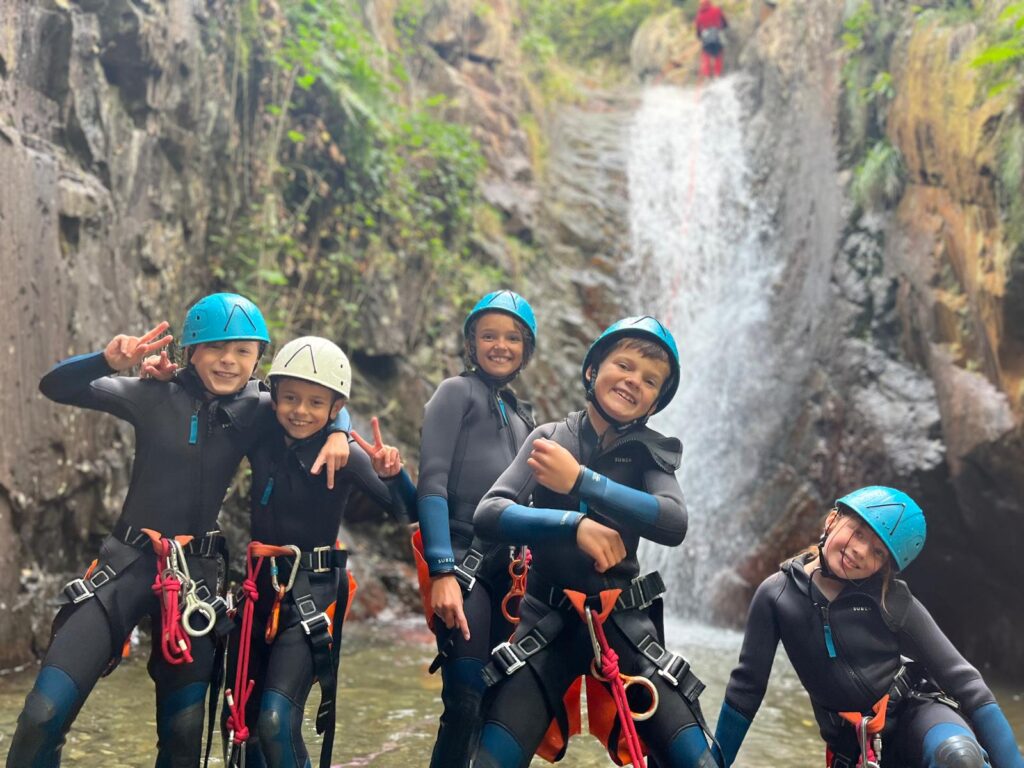 Groupe d'enfants posant devant une cascade pendant une session de canyoning.